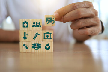 Man's hand on wooden blocks with icons of various types of insurance. Life health insurance and hospital concept.