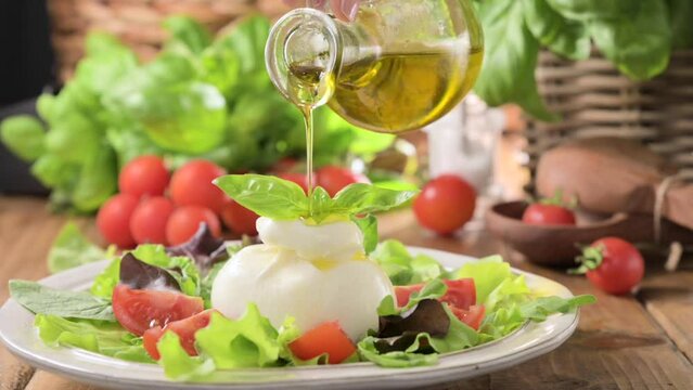 Salad with Tomatoes, Burrata, basil,olive oil. middle name Burratina. Traditional cheese from the south of Italy in the Puglia region. Round soft cheese inside liquid stracciatella texture 