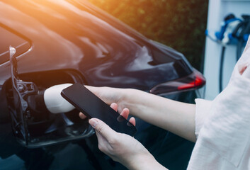 Hand plugging in a charger in an electric car socket.Electric car or ev is charging at station