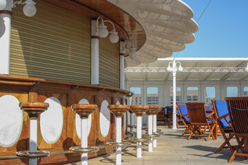 View from open outdoor deck of legendary luxury ocean liner cruise ship with deck chairs, railing...