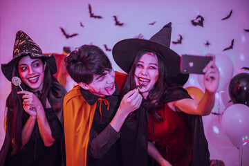 Obraz premium Asian young people in costumes celebrating halloween. Group of friends having fun at party in nightclub.