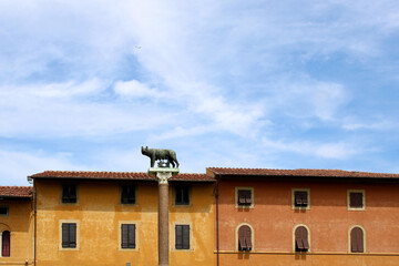 Fototapeta na wymiar Statua della Lupa Capitolina a Pisa con facciata e finestre e cielo