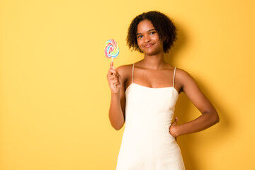 Cheerful young african american girl in casual summer dress isolated on yellow background studio portrait. People lifestyle concept. Mock up copy space.