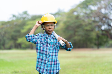 African American child boy in engineering holding construction blueprint and wearing yellow safety...