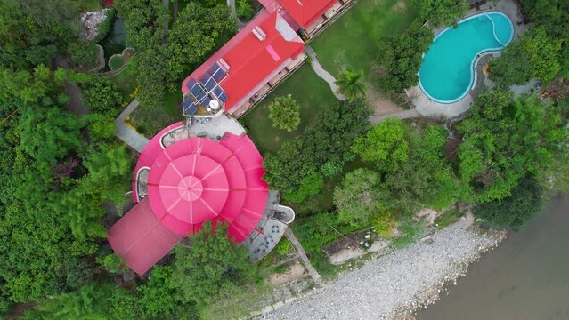 flat top down aerial drone shot showing the red roofs of resort nestled between green tress with swimming pool and cottages located at jim corbett park in India