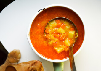 The cat steals food. Top view, yellow tomato soup in a pot