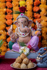 A Beautiful clay statue/Idol of an Indian god Lord Ganesha decorated with colourful Marigold garland 