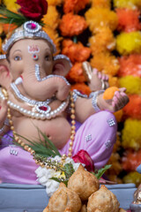 A Beautiful clay statue/Idol of an Indian god Lord Ganesha decorated with colourful Marigold garland 