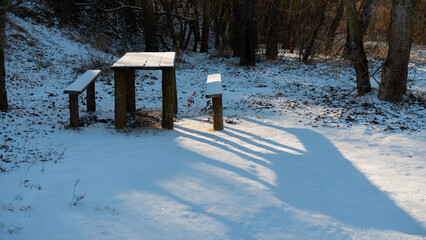 Tables and benches in the forest are covered with snow. January. Web banner.