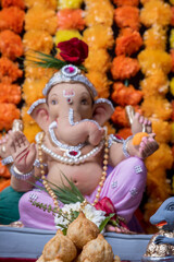 A Beautiful clay statue/Idol of an Indian god Lord Ganesha decorated with colourful Marigold garland 