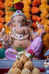 A Beautiful clay statue/Idol of an Indian god Lord Ganesha decorated with colourful Marigold garland 