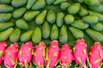 Pile of pitaya or dragon fruit, Big Bunch of Pink Dragon Fruits and green organic avocado in the market, in traditional Market, Copy space.
