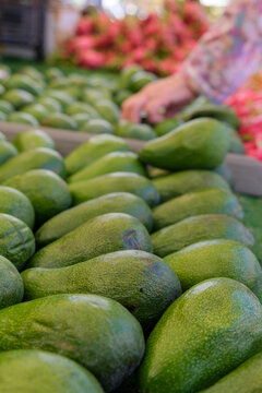 Top view of a bunch of green organic avocado fruits in the market, vertical image, copy space.