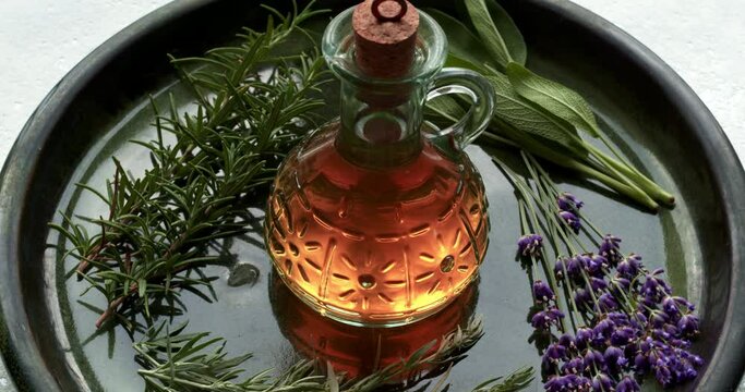 Herbs infused vinegar in bottle. Thieves vinegar, alternative medicine remedy with wormwood, sage, rosemary and lavender. Herbalism concept. Table spin.