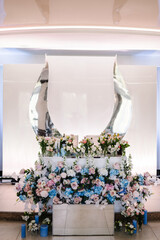 Festive table, arch, stand decorated with a composition of blue, pink flowers and greenery, candles in the banquet hall. Table newlyweds in the banquet area at the wedding party.