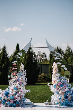 Location for the wedding ceremony. Arch for wedding ceremony a is decorated with flowers and greens, greenery. Wedding decor on backyard banquet area.