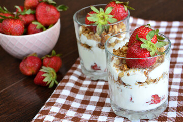 healthy dessert with yoghurt, granola and strawberry in drinking glasses, close-up