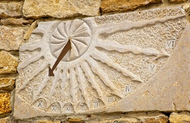Stone sundial with metal gnomon on side of stone building in the Provence, France. - obrazy, fototapety, plakaty