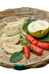 closeup the bunch ripe yellow white guava fruit sliced with red chilly and green leaf in the brown basket soft focus natural  white brown background.