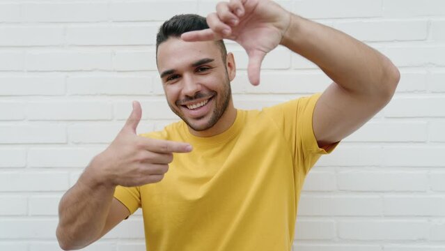 Young hispanic man smiling confident doing photo gesture with hands over isolated white background