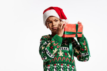 Annoyed child in a knitted colorful sweater holds box in festive package. Boy rejoices at holiday, Christmas, New Year.