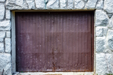 A closed garage door in a stone wall