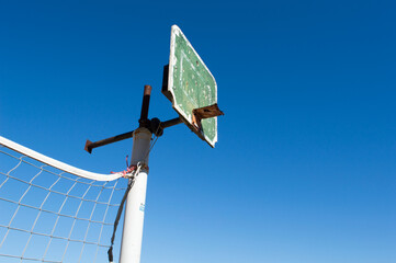 Old and damaged basketball board, against clear blue sky
