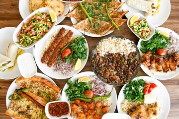 Delicious meat kebab with fresh vegetable salad served with variety of Turkish dishes and appetizers. Top view of assorted Turkish food and meze, tasty and healthy Mediterranean cuisine.