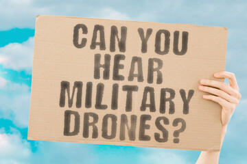 The question " Can you hear military drones? " on a banner in men's hands with blurred background. Army. Camera. Deadly. Armed. Modern. Hearing. Find. Hear. Sound. Voice. Earphones. Controlled. Spying