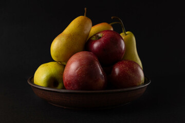 Apples and pears. Apples and pears in a plate on a dark background.