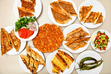 Traditional Turkish cuisine. Pizza, pita, pidesi, sucuk, hummus, kebab. Many dishes on the table. Serving dishes in restaurant. Background image. Top view, flat lay