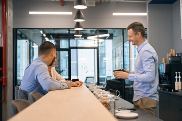 Joyous company employee and his two colleagues in office kitchen