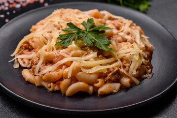 Tasty appetizing classic italian pasta with tomato sauce and cheese on plate on dark background