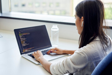 Closeup of female programmer writing code on laptop