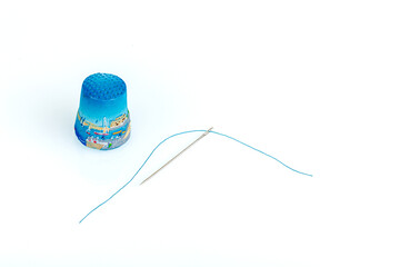thimble and needle and thread on a white background - obrazy, fototapety, plakaty
