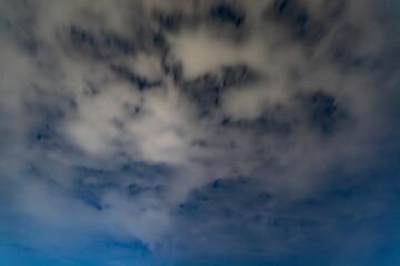Dark blue sky on long exposure with moving clouds at night