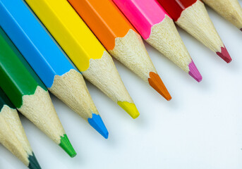 Close-up of colorful pencils arranged in a row, showcasing vibrant hues and sharp points against a white background.  Perfect for creativity and art-related projects.