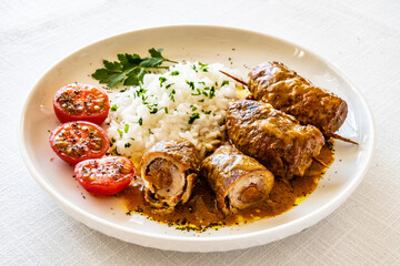 Wrapped pork served with white rice and cherry tomatoes  on white table