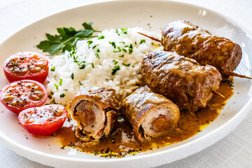 Wrapped pork served with white rice and cherry tomatoes  on white table