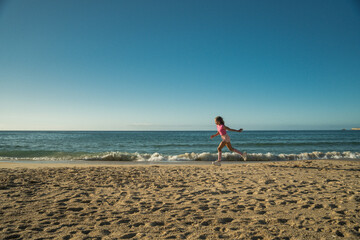 Girl running through the beach with hot sand and having fun while spending time at the ocean