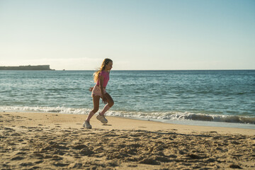 Happy caucasian girl running on sand against ocean while having fun at the beach