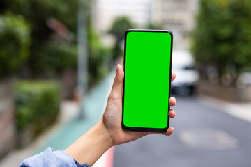 Woman hold with green screen cellphone at street