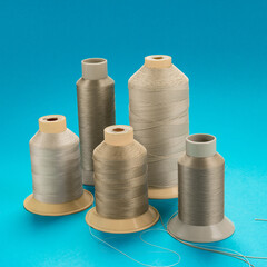 spools of beige polyester thread on a blue background