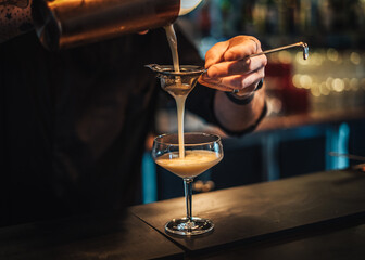 Landscape photo of bartender mixing a cocktail at a moody cocktail bar