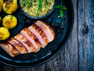 Roast pork loin with fried potatoes and cabbage on wooden table