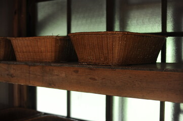 Fototapeta na wymiar Rattan woven wicker baskets or caskets on a shelve in dark room