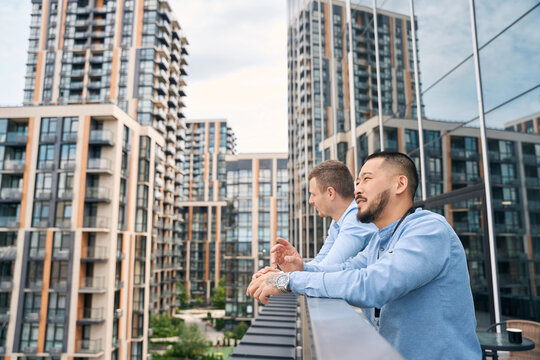 Two thoughtful company employees standing on office balcony