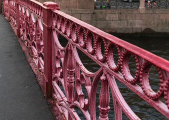 Fragment of an old forged metal fence of the red bridge.