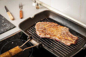 Veal steak on a grill on a ceramic hob, cooked at home.