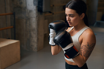 Sportswoman boxer fighting in gloves with concentrated face
